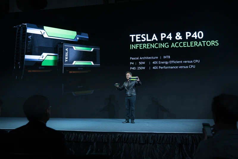 Jensen Huang on stage at GTC Taiwan 2016, holding graphics accelerators in front of a Tesla P4 and P40 display.